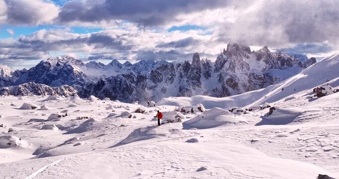 Aerial footage of a ski mountaineer in a snowy alpine ridge in Dolomites. Winter landscape, backcountry adventure, and solitude in breathtaking mountain scenery captured in 4K.
