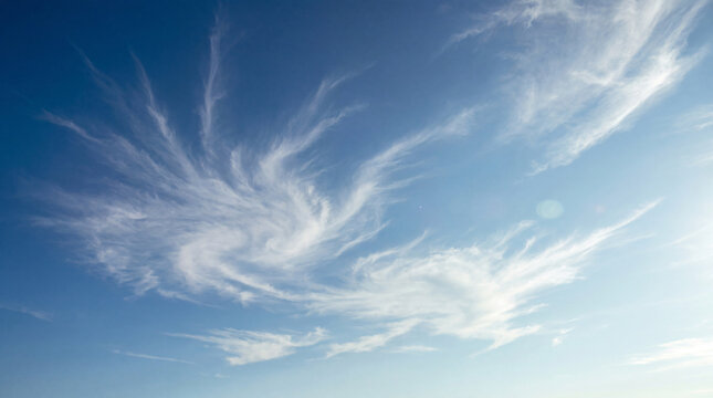 Dynamic photograph of a bright blue sky filled with swirling, ethereal cirrus clouds.