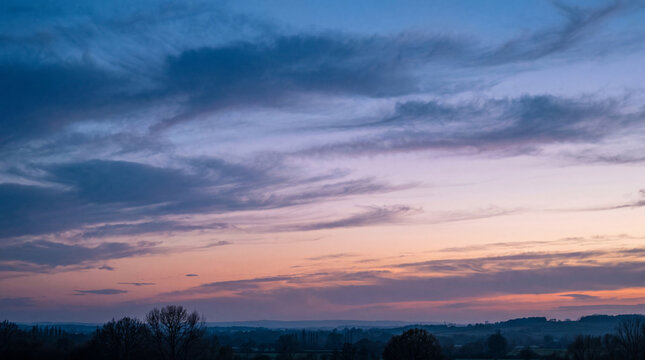 Beautiful rural landscape photography at twilight featuring vibrant sky and silhouetted trees.