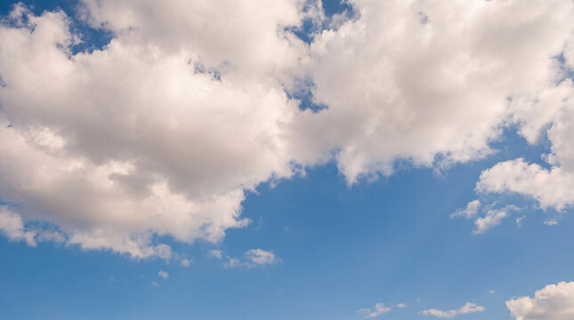 Clear blue sky with scattered fluffy white cumulus clouds creating a dynamic and open outdoor backdrop.