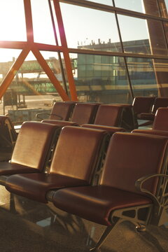 Empty waiting area seats inside a modern terminal with large glass windows and warm sunset light.