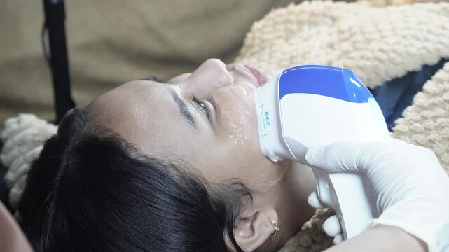 Female patient receiving HIFU treatment at an aesthetic clinic for jawline lifting, skin tightening and facial contouring