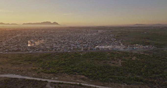 Cape Town South Africa Aerial v113 sunset flyover above Macassar and Baden Powell Drive toward dense Khayelitsha township housing and mountains - Shot with Mavic 3 Pro Cine - Jan 11th 2024