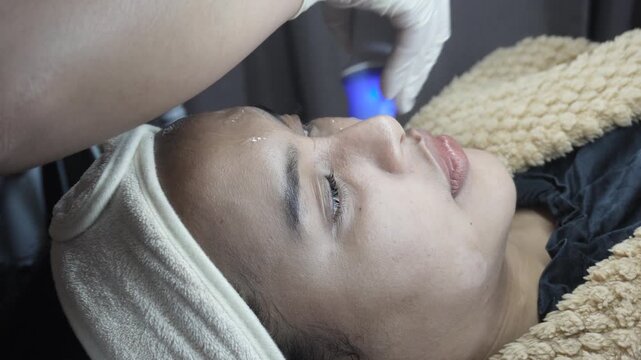 Female patient receiving dual radiofrequency and ultrasound facial treatment at an aesthetic clinic for skin tightening.