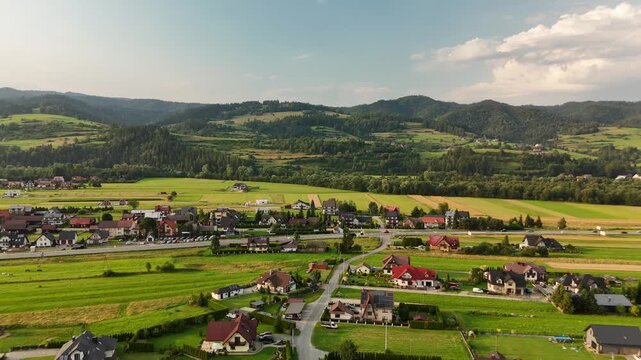 Aerial view of a village with houses and fields in a valley below forested hills in Poland in summer