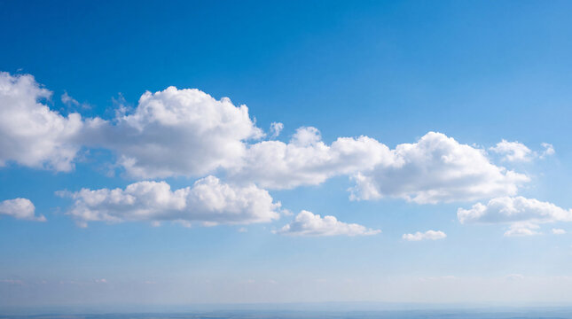 Vibrant blue sky with scattered fluffy white cumulus clouds, forming a serene and expansive natural backdrop.
