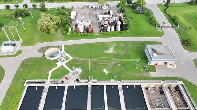 Aerial view tracking backward from a top-down view of large industrial clarification pools, filtration grids, and tanks at a municipal water processing plant