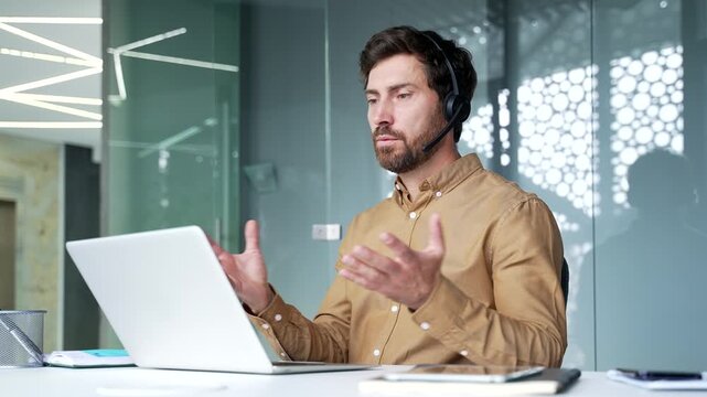 Mature businessman wearing a headset while leading an online business training session in a modern office. Confident professional presenting ideas and engaging with participants during a live workshop