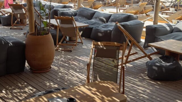 A large terracotta planter sits beside dark cushioned sofas and wooden tables on a shaded resort terrace