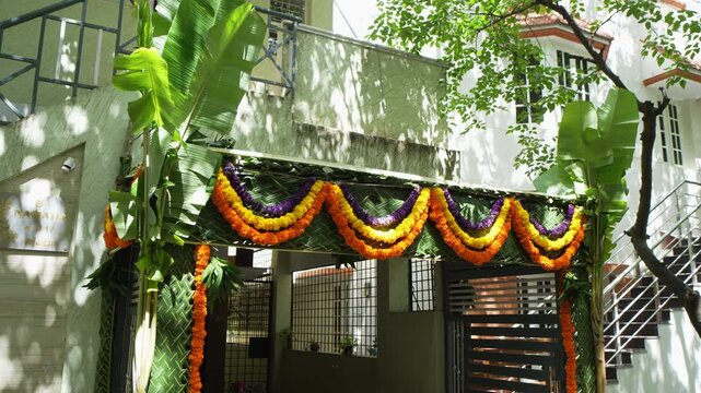 Colorful chapra wedding entrance with banana trees and marigold garlands outside a South Indian home in bright daylight.