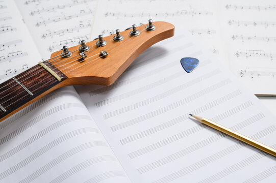 Musical creativity. Music notebook, pencil, and guitar. Selective focus, white space.