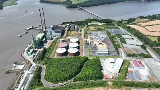 Drone orbit. Elevated drone perspective of electricity infrastructure on the River Suir, County Wexford. Sustainable energy facility surrounded by natural Irish landscapes and peaceful river scenery.