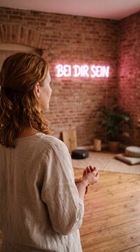 Neonschrift BEI DIR SEIN im Meditationsraum &uuml;ber die Schulter