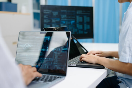 Two software developers collaborating with laptop and tablet, reviewing source code and digital dashboards in a modern office for programming and software development.