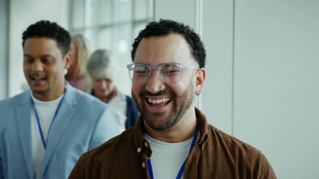 A group of engaged business professionals, including two men laughing and smiling, are seen networking and enjoying a lively conference or corporate event, fostering positive interactions.