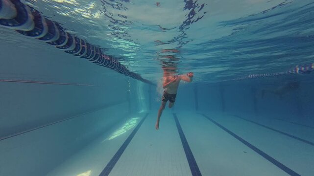 Young Swimmer Diving Underwater in Swimming Pool Lane