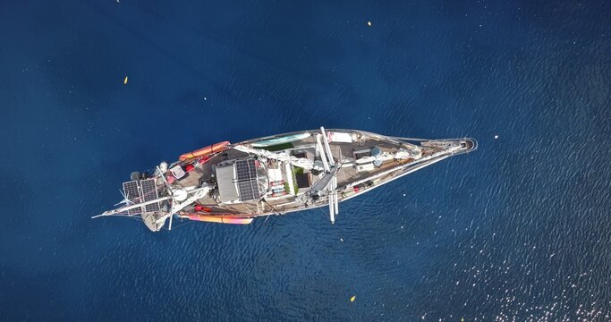 Aerial view of a sailboat floating on deep blue water with solar panels and kayaks visible on deck in Port Resolution, Tanna Island, Vanuatu.