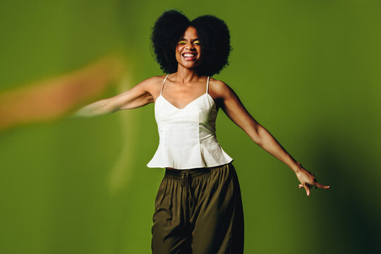 Woman dances with smiling energy in a green background studio portrait