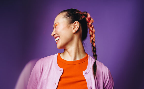 Laughing woman with braided hair brings joyful energy to the studio portrait