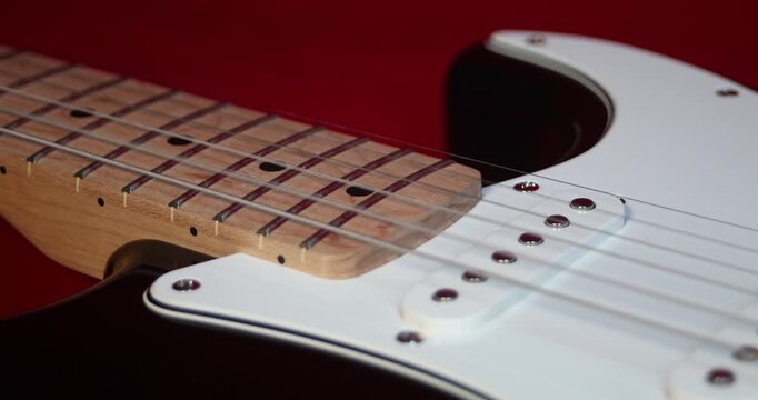 Macro shot of guitar strings and fretboard, red background