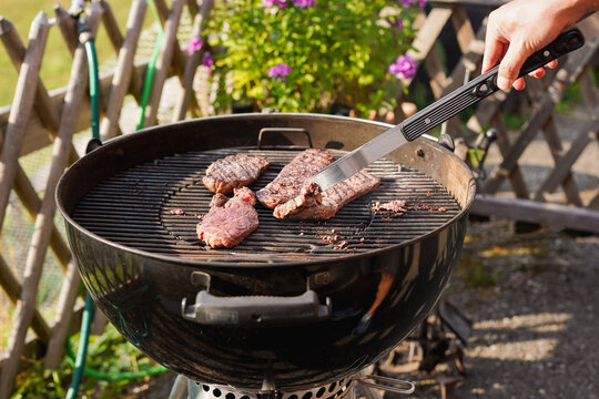 Man cooking meat on barbecue grill outdoor during summer weekend day - Food, lifestyle and holiday concept