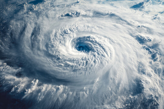 A detailed satellite view capturing the swirling eye and towering clouds of a powerful hurricane storm forming over the ocean's vast surface at daylight
