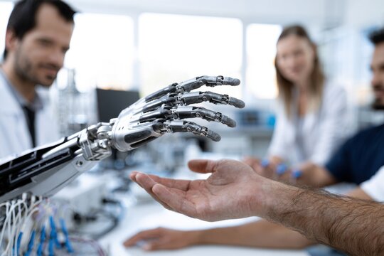 Engineers testing advanced robotic hand in modern laboratory as human hand reaches out in collaborative interaction with cutting-edge technology development