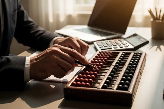Man uses old abacus for finance calculations at his desk. Laptop and calculator nearby show contrast between old and new accounting methods.