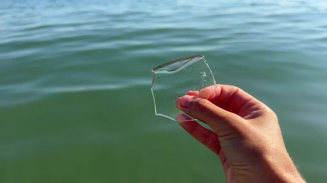 Female hand holding a piece of glass found on the seabed in shallow seawater. 4k