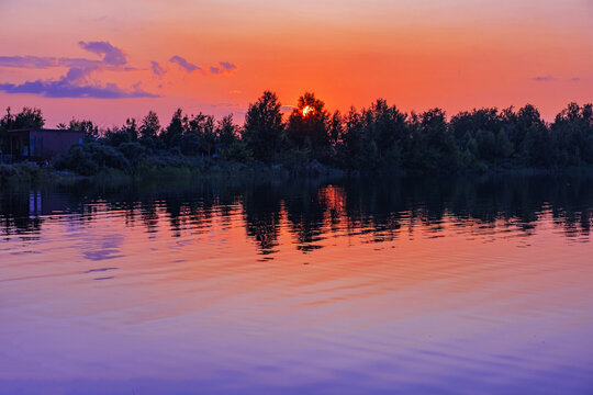 Beautiful sunset over Ulken Shabakty lake in Kazakhstan. Rd blue gradient sky with colored clouds and ripples on calm water. Serene twilight lake pastel color landscape. Dreamy romance evening.