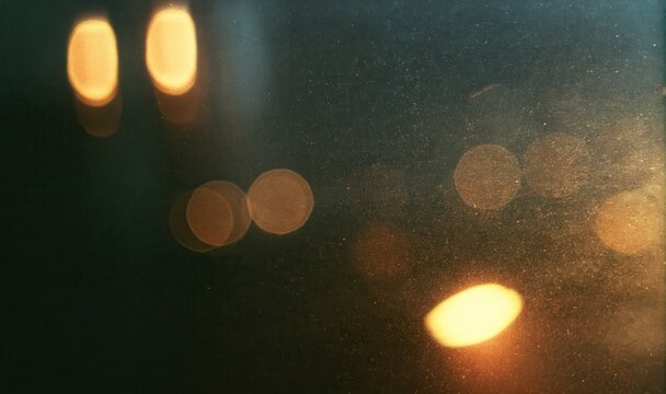 Abstract dark background template with warm yellow golden bokeh light orbs and heavy noise sand texture for design banner copy space