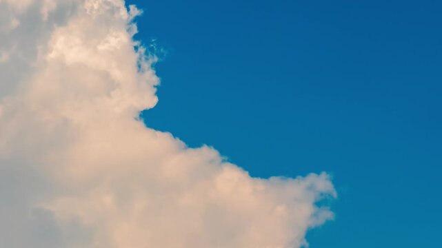 Time lapse of fluffy white cloud billowing and rolling across a clear blue sky with negative space for text overlays, raw atmospheric weather changes and natural meteorological patterns in the sky