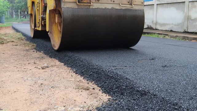 Asphalt road construction, Large yellow steamroller flattened hot asphalt, Builds new road