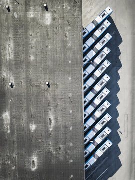 Aerial view of a row of parked buses aligned next to a large concrete wall in Hisingen, Gothenburg, Vastra Gotaland County, Sweden.