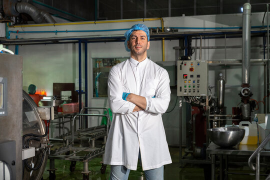 Food scientist worker in sterile clothes standing in food factory, look at camera. 