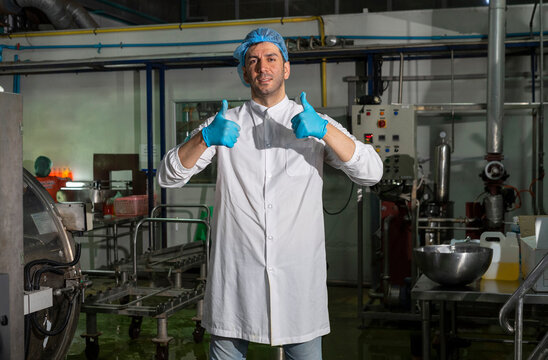 Food scientist worker in sterile clothes standing in food factory, look at camera. 