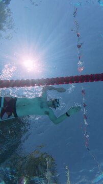 Low Angle Underwater View of Man Swimming with Fins in Pool