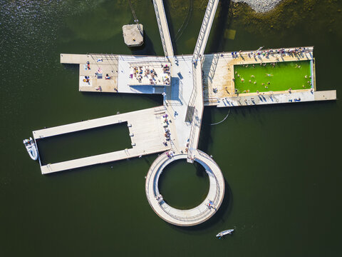 Aerial view of the Pol Harbor public swimming pool with its distinctive circular and rectangular pools, wooden decks, and people enjoying the sunny weather in Goteborg, Vastra Gotalands lan, Sweden.