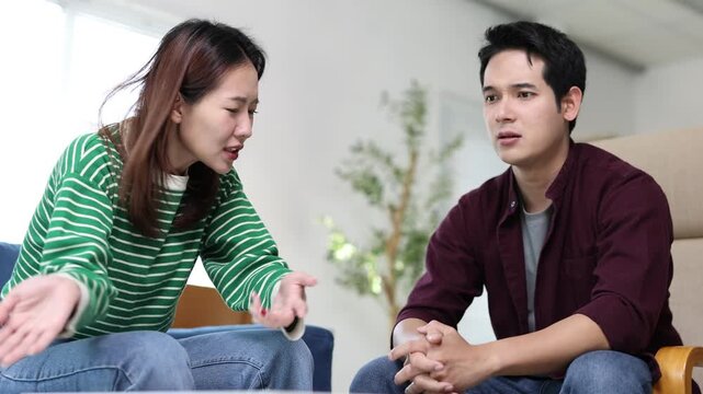 Young couple arguing about financial problems, showing empty wallet and unpaid bills on the table.