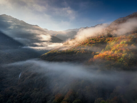 Aerial view of Sutjeska National Park with autumn foliage and mist rolling through the mountains during golden hour in Tjentiste, Republika Srpska, Bosnia and Herzegovina.