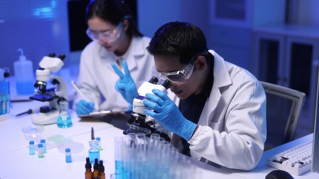 Male and female scientists sit and conduct experiments in a laboratory.