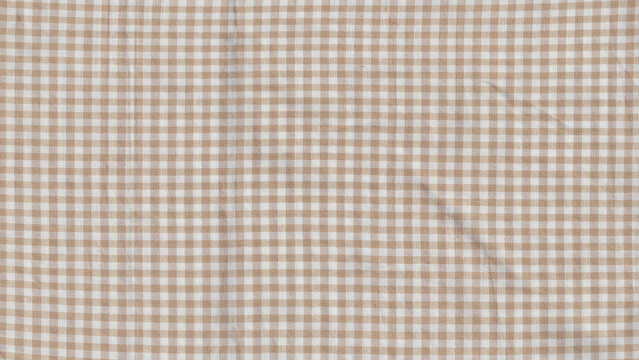 Flat light brown and white gingham checkered fabric texture background.