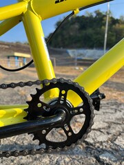 Fototapeta premium BMX Bicycle Drivetrain and Chainring Component Displayed Outdoors on Asphalt Road. Detailed bicycle crankset and chainring photographed in natural light for cycling and mechanical themes.
