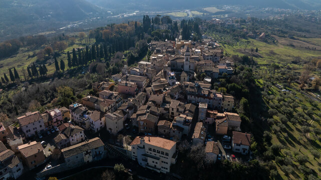 Aerial view of the historic hilltop town of Mandela, featuring stone buildings, terracotta rooftops, and narrow streets surrounded by olive groves and rolling hills in Mandela, Lazio, Italy.