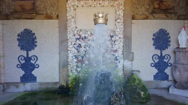 Floating gilded coronet fountain at Arundel Castle, hovering on a vertical water jet inside Oberon's Palace shell grotto in the Collector Earl's Garden, West Sussex, UK.