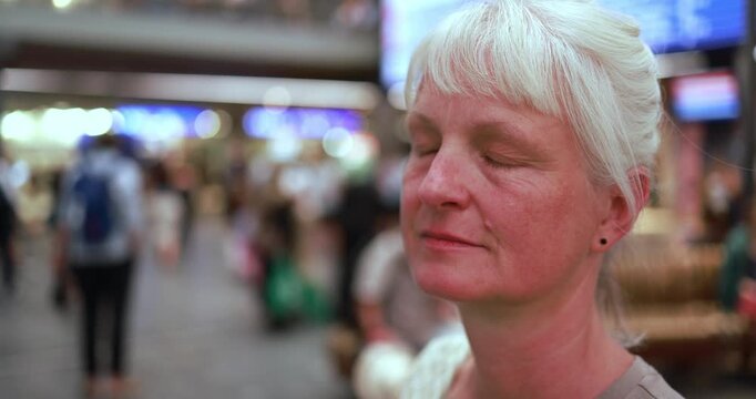 Caucasian senior woman looking at camera inside train station - Urban lifestyle and travel concept - UGC content - Main focus on face