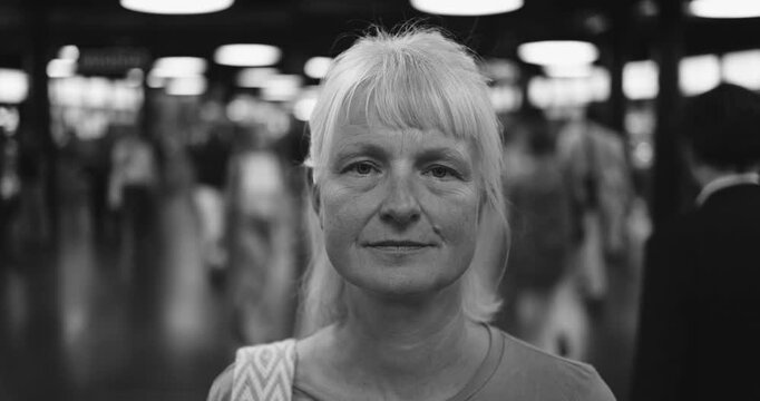 Caucasian senior woman looking at camera at subway - Urban lifestyle and travel concept - Black and white editing - UGC content - Main focus on face