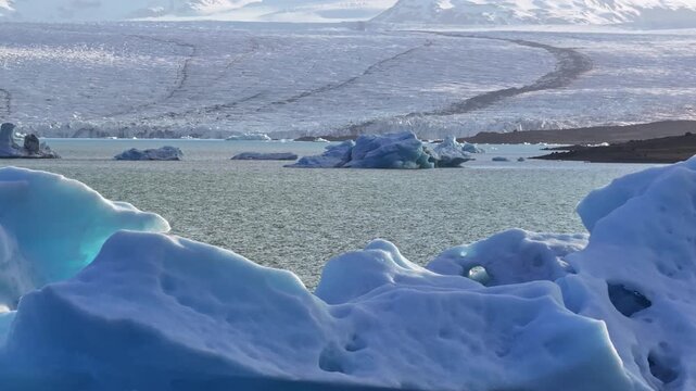 Icebergs in lake by melting glacier in sunny Iceland, slow pan