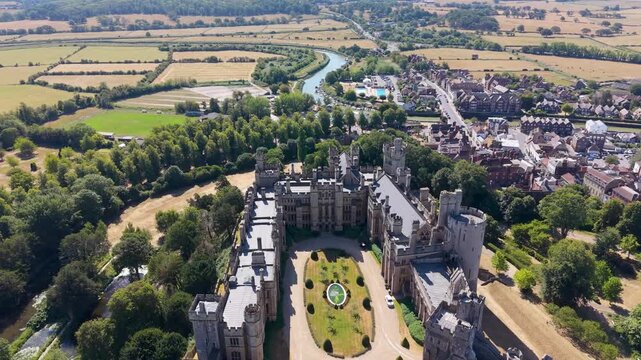 Arundel castle drone flyover moving rear to front above the historic fortifications, Arundel town on the right and River Arun beyond, bright clear summer weather, England, UK.