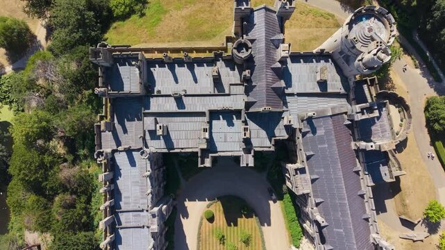 Arundel Castle top-down aerial reverse pan over medieval turrets, fortified walls and inner courtyard, revealing historic architecture, rooftops, shadows and garden patterns in England.